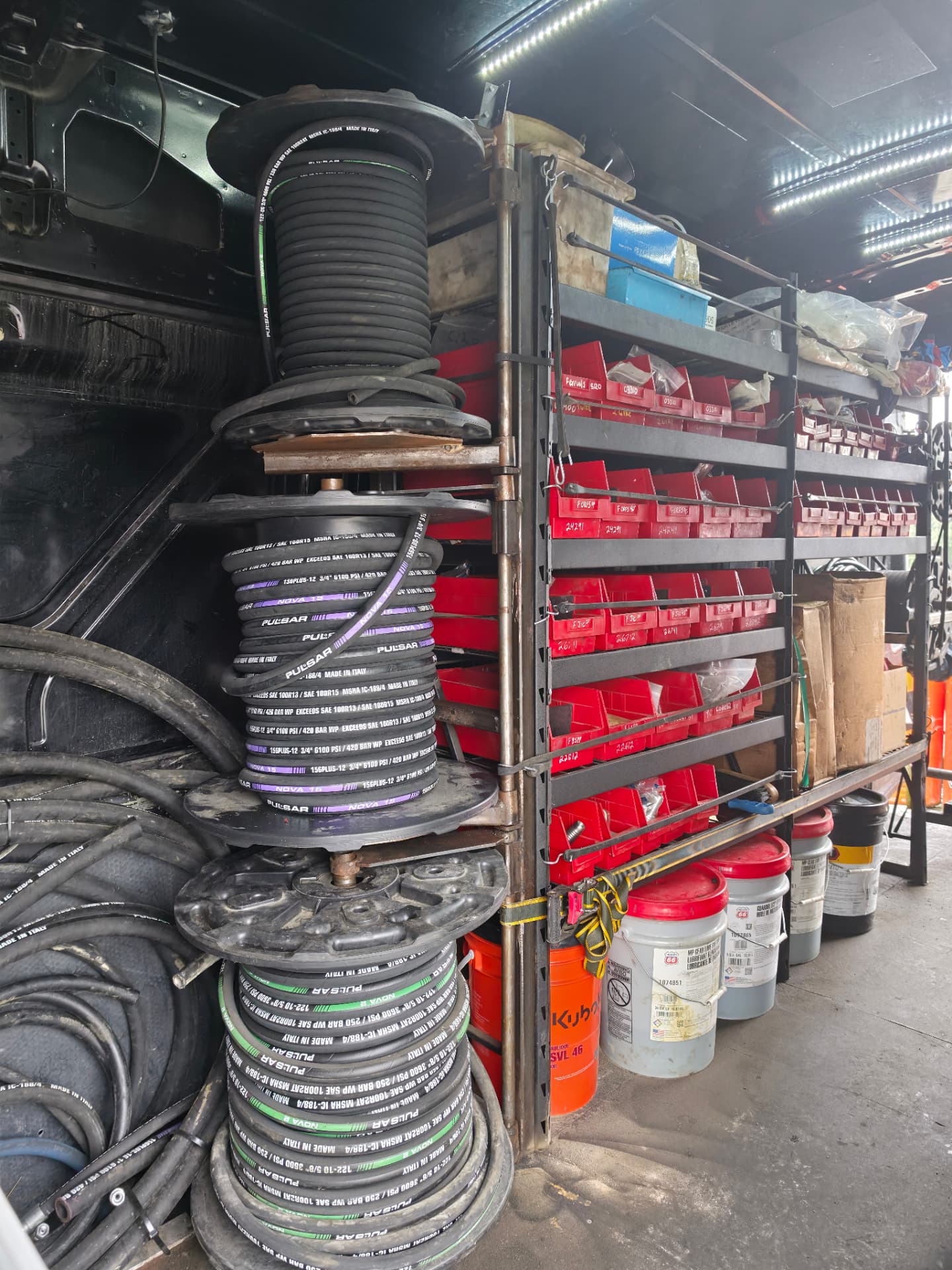 Hydraulic hose stock and red parts bins inside the van